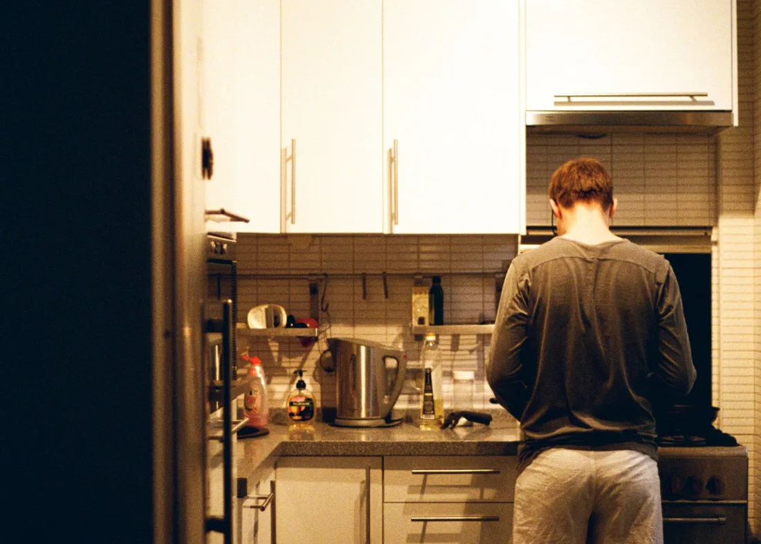 A person cooking a late meal alone in a small kitchen at night
