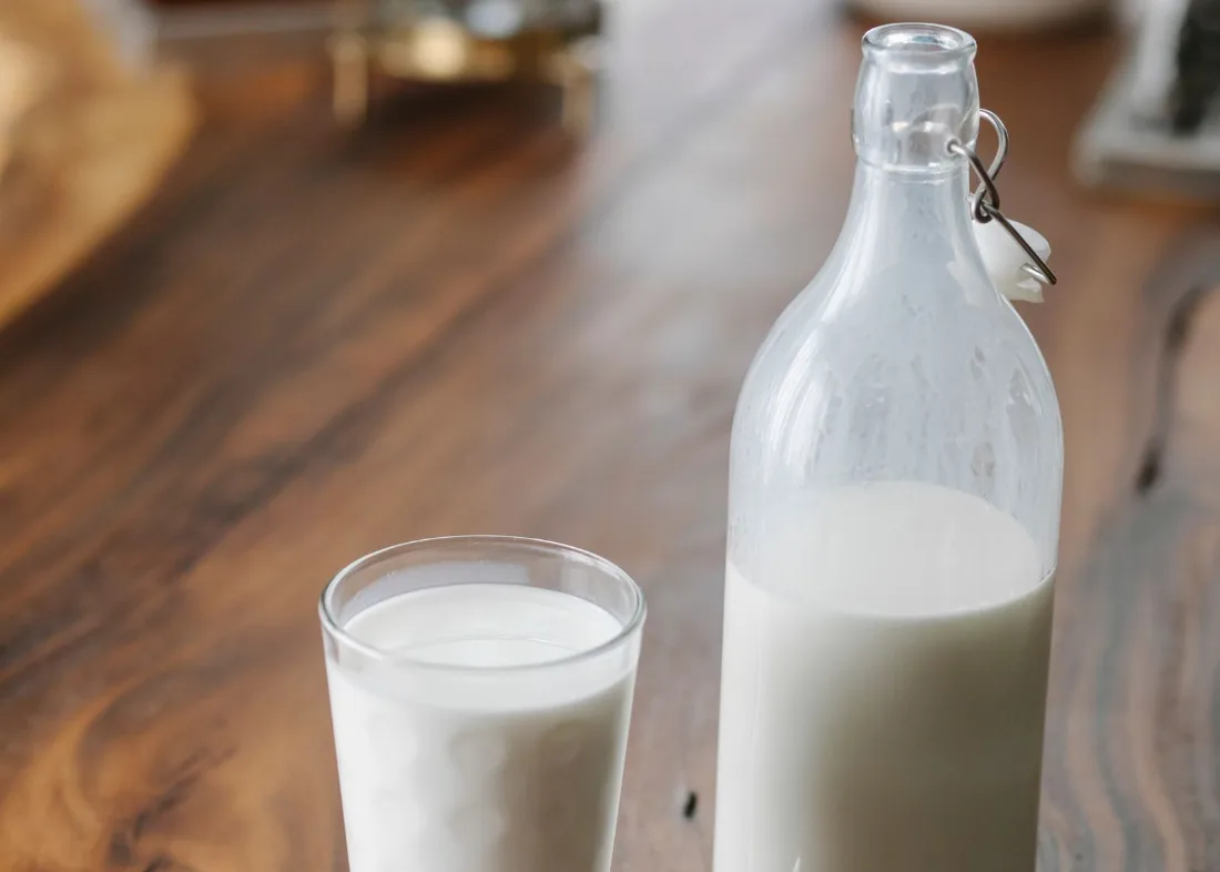 A glass and a bottle of milk on a wooden table, a reminder that milk fills a child up before meals do